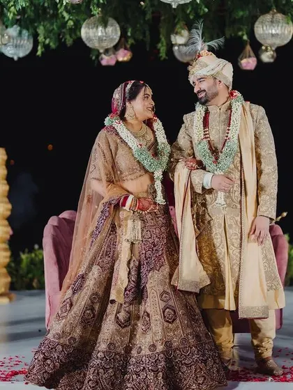A beautiful couple portrait on their wedding day, standing under a canopy of hanging flowers and greenery.