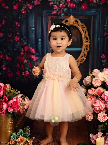 A beautiful indoor portrait of a little girl in a floral wonderland. The soft lighting and pastel colors create a dreamy, painterly effect.