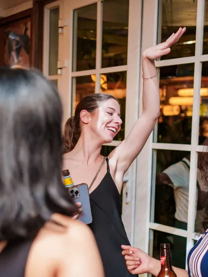 A guest with a huge smile, arm in the air, having the time of her life at our THROWBACKS Edition.