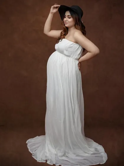 Adding a little flair with a stylish hat. This portrait in a simple white gown against a brown backdrop shows how a single prop can change the vibe of a photo.