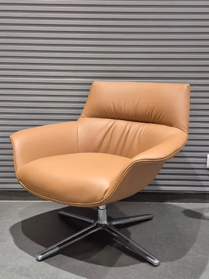 An angled view of the tan swivel lounge chair, showing its inviting and ergonomic shape.