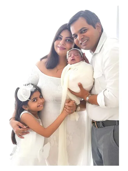 A timeless family portrait celebrating a new arrival. Dressed in classic white, this family's love shines through, creating an elegant and heartwarming image perfect for displaying in your home.