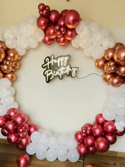 A chic birthday balloon ring with clusters of metallic red, rose gold, and white balloons.