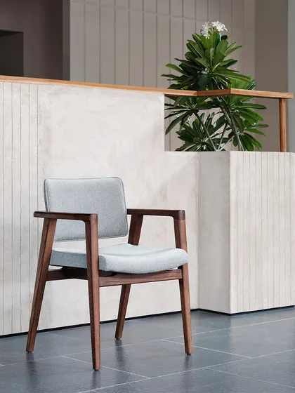 Our intent was to treat each piece of furniture as a work of art within a home-like environment. Here, a simple chair is set against a backdrop of textured plaster and wood, highlighting its form and material.