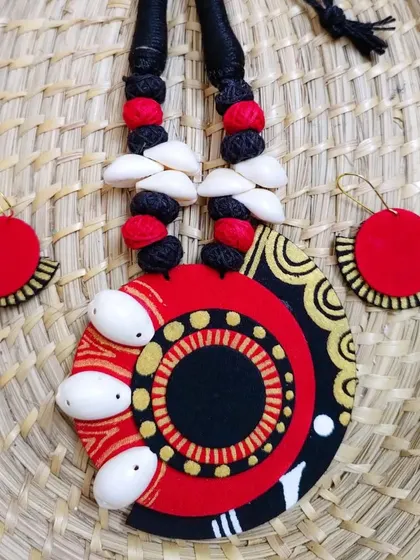 A large, circular fabric pendant with cowrie shells and hand-painted details. This is a statement piece that is surprisingly lightweight and comfortable to wear.