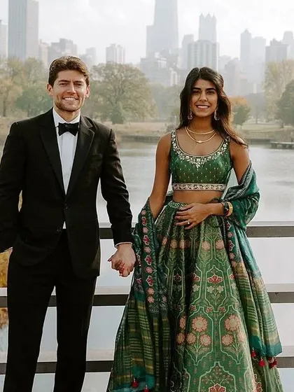 This couple's look is a great example of fusion wear. I can design a similar printed green lehenga for her, which pairs beautifully with his classic tuxedo for a modern reception.