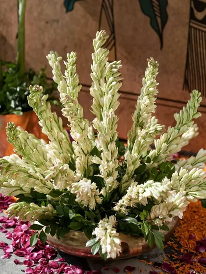 A close-up of a brass bowl filled with fragrant tuberoses, a classic flower in Indian wedding decor.
