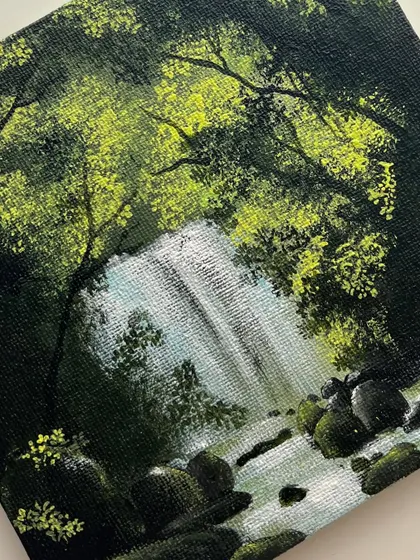 A close up shot of the small forest waterfall painting, highlighting the texture of the leaves and the flow of the water.