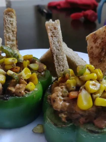 An innovative snack of bell peppers stuffed with a savory corn and vegetable mixture, served with toasted bread soldiers.