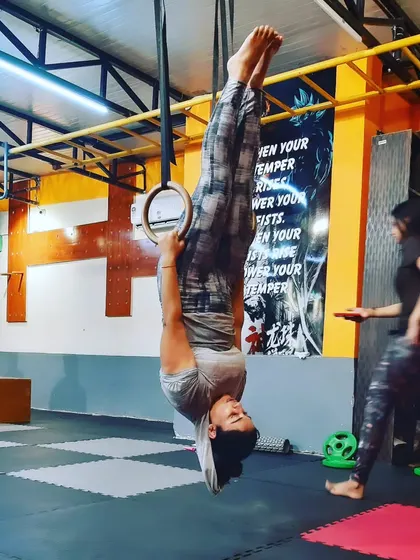 A female member showing incredible strength and control, holding an inverted position on gymnastic rings.