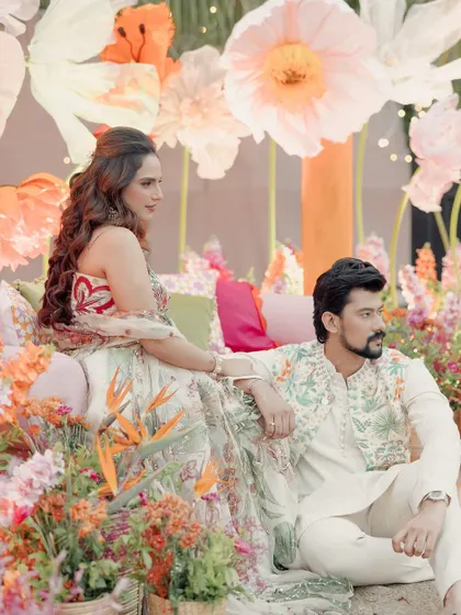 A beautiful portrait of the couple amidst a stunning floral backdrop. Janvi's soft curls and radiant makeup are perfect for a daytime Mehendi.