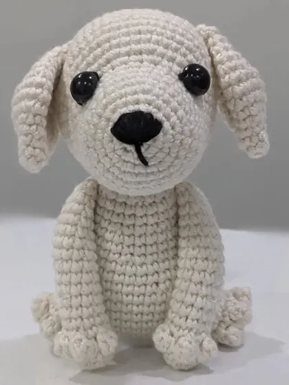 A handmade amigurumi dog named Milky, sitting patiently. This is a simple yet charming representation of a white puppy.