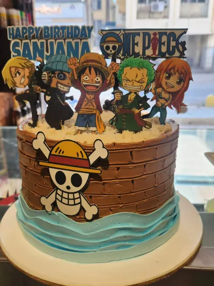 Set sail on a sweet adventure with this One Piece anime theme cake. It features the Straw Hat Pirates crew and a chocolate frosting base designed to look like a pirate ship.