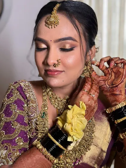 A close-up of the bride getting her final touches. The golden eyeshadow and winged liner are classic choices for a South Indian muhurtham look, paired with a traditional nose ring.