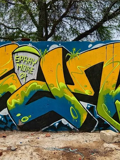 A yellow and blue piece from the 'Spray More' jam. This one has a classic, bubbly graffiti style with bold outlines.