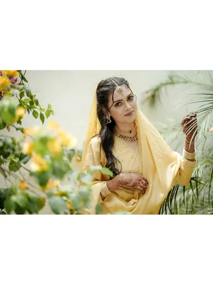 A duplicate of a lovely portrait of a bride in a soft yellow outfit, framed by yellow flowers that complement her attire perfectly.