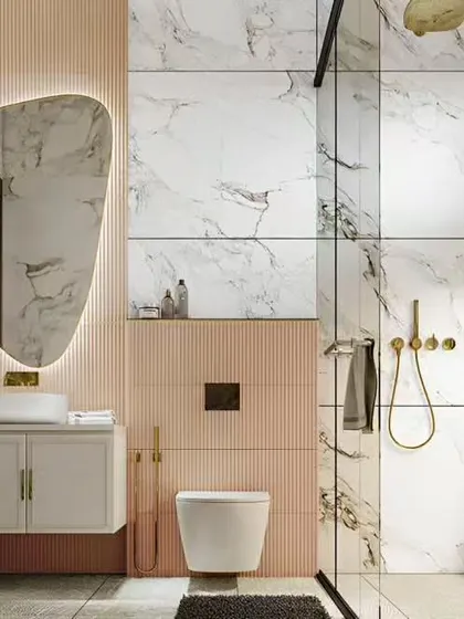 This luxurious bathroom design pairs large-format marble-style tiles with soft pink fluted panels. The organic-shaped backlit mirror and gold fixtures add a final touch of elegance.