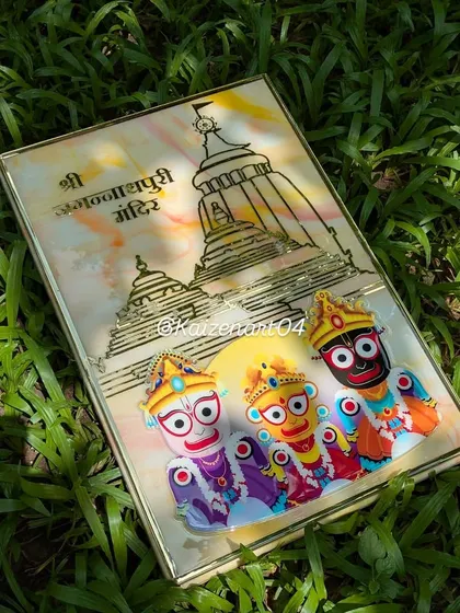The Shri Jagannath Puri temple frame, photographed outdoors. The natural light brings out the warm colors in the marble-effect background and the glossy shine of the resin.
