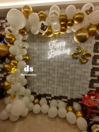 Another perspective of the white and gold 25th birthday setup, showing the full balloon arch.