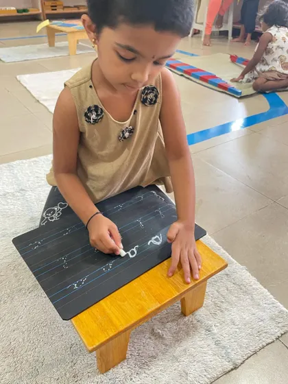 The journey to writing is a gradual process. Here, children practice forming letters and numbers, building on the fine motor control and concentration they have developed through countless practical life and sensorial activities.