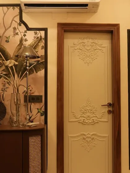 This image showcases the same bedroom, focusing on the interplay between the vintage-style carved door and the tropical-themed wall art. The design is a perfect example of blending different styles to create a unique look.