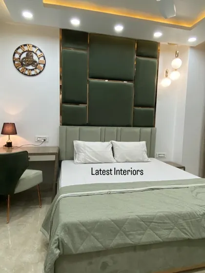 Another view of the green-themed bedroom, showing the compact study desk and chair that match the room's color scheme. The large wall clock adds a classic touch.