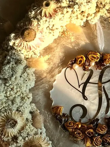 A close-up of the hanging logo wreath, showing the detail of the preserved flowers and the custom initial logo. It's a beautiful way to celebrate a new union.