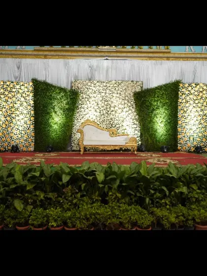 A wider perspective of a modern stage design, showing how the angled green and floral panels create a powerful visual impact. The potted plants at the front of the stage help blend the decor with the venue.