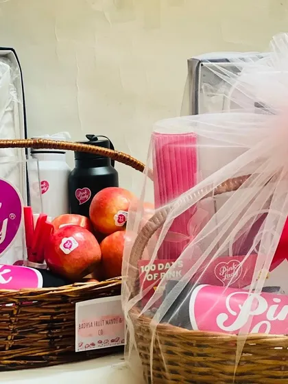 A pair of 'Pink Lady' themed corporate gift baskets, one open and one wrapped, showing the full contents and the final presentation.