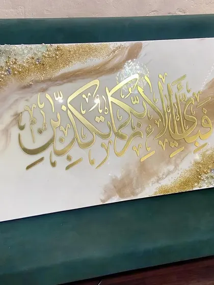 A wide view of the Surah Ar-Rahman verse artwork, displayed on a green couch to show its size and how it complements home decor.