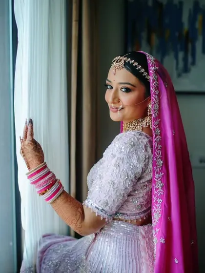 A lovely portrait of the bride looking out the window, her bright pink dupatta adding a pop of color.