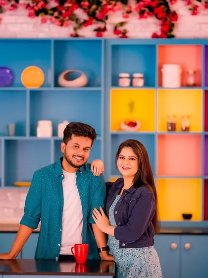 A happy, relaxed portrait of a couple in a colorful kitchen. Their casual outfits and the bright, fun setting make for a very lively and personal photo.