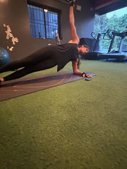 A client demonstrates a perfect side plank with an arm raise, an excellent exercise for targeting the obliques and improving rotational stability.