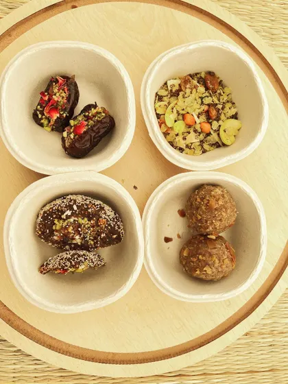 A sampler plate of my healthy sweets, featuring gourmet stuffed dates, energy laddus, and a slice of a nutty date bar. It’s the perfect way to enjoy a variety of guilt-free desserts.