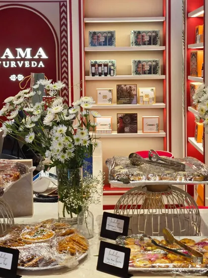 Our grazing setup inside Kama Ayurveda places covered platters and little dishes on stands, with white flowers in front of the shelves.