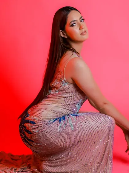 This pose shows the back and side details of the multi-colored gown, highlighting its unique design from every angle.