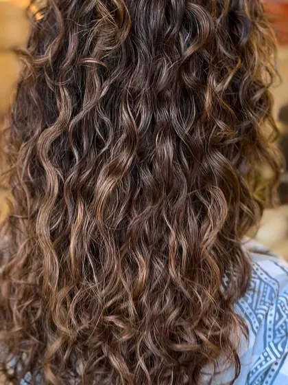 A brunette balayage on beautiful natural curls. The highlights are painted on to follow the curl pattern, enhancing the texture and shape.