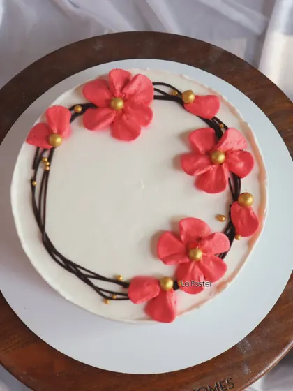 A simple yet beautiful cake with a wreath of hand-piped pink flowers with golden centers.