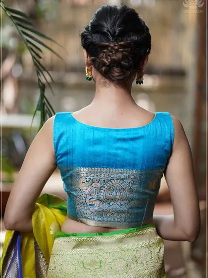 A back view of a bright blue silk blouse with a wide, woven brocade border, showcasing traditional craftsmanship.