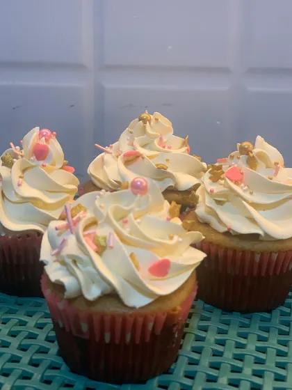 Simple and sweet vanilla buttercream cupcakes. These are topped with a classic swirl and a mix of pink heart and gold star sprinkles, perfect for any occasion that calls for a simple, delicious treat.