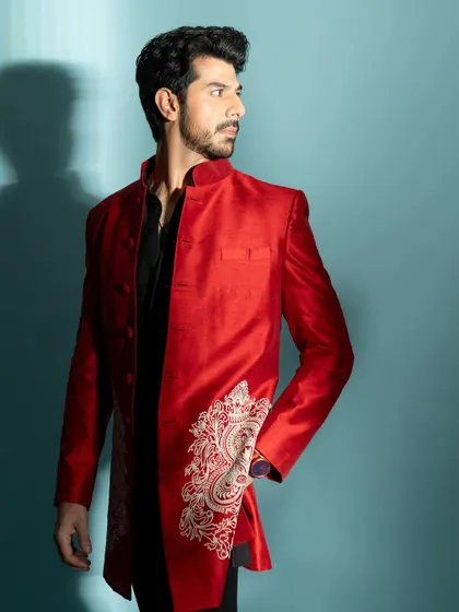 A three-quarter shot showcasing a modern Indian wear look. The vibrant red jacket provides a strong pop of color.