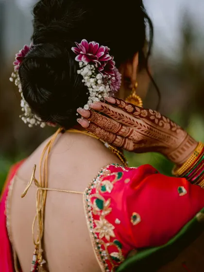 A detail shot focusing on the bride's intricate hairstyle, adorned with fresh flowers, and her mehendi.