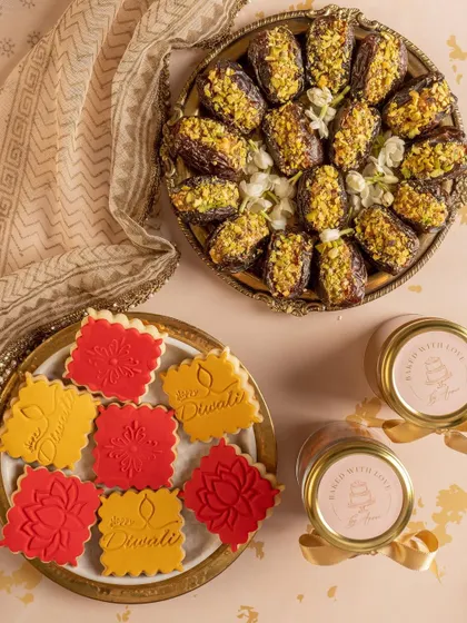 A flat-lay of Diwali sweets, including stamped cookies and pistachio-covered dates. This image highlights the intricate details and festive nature of the products.