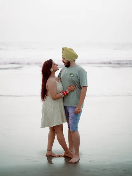 A classic beach portrait. The couple stands together, smiling, creating a beautiful memory of their time in Goa. The bride's red bangles add a lovely pop of color.