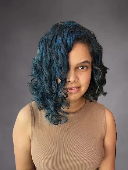 A curly asymmetrical bob with bold blue highlights for Nikita. A fun way to express your personality with color.