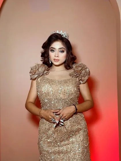 A close-up of a model wearing a golden sequined gown with a tiara. This look is perfect for a bride who wants to feel like a princess at her reception.