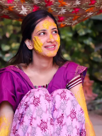 A thoughtful and happy portrait of the bride during her Haldi. She looks off to the side with a gentle smile, soaking in the moments of her celebration.