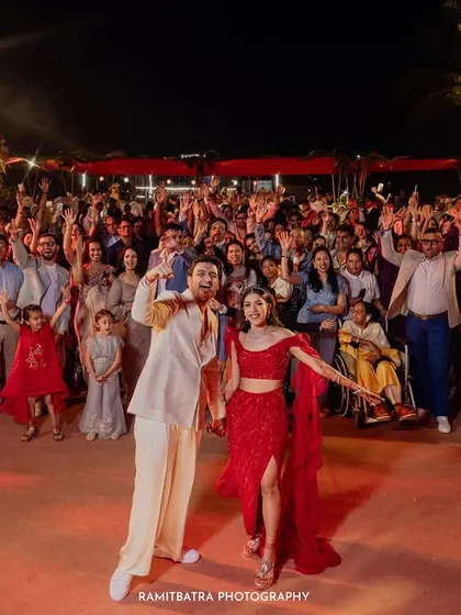 The entire wedding party poses for a massive group photo on the dance floor at a vibrant beachside reception in Goa.