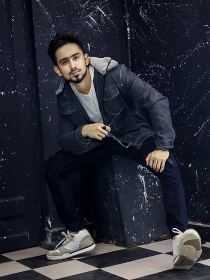 A moody, urban-style studio shoot with a textured black background and a checkerboard floor.