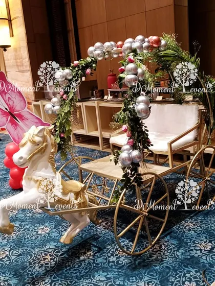 A magical horse-drawn carriage prop decorated with greenery and silver balloons, perfect for a princess or fairytale-themed baby entry or photo op.